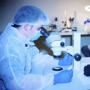 scientist analyzing a sample through a microscope